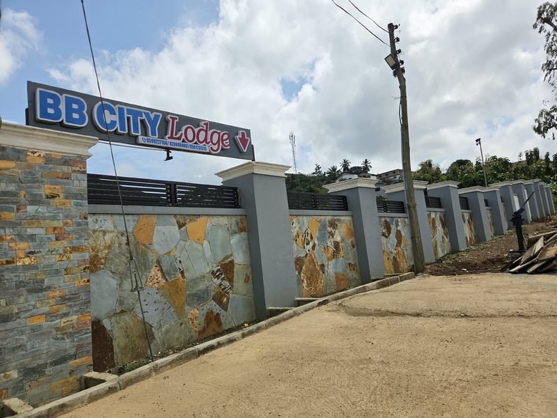 The BB City Lodge entrance sign mounted above the stone wall on the approach road